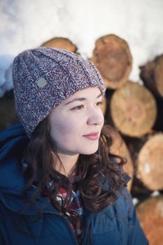 the beautiful young girl in a warm cap from wool of the alpaca in the winter forest. knitting