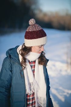 the beautiful young girl in a warm cap from wool of the alpaca in the winter forest. knitting