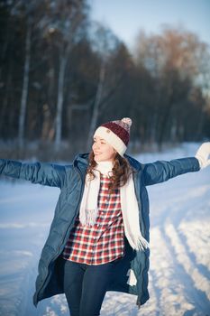 the beautiful young girl in a warm cap from wool of the alpaca in the winter forest. knitting