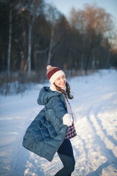 the beautiful young girl in a warm cap from wool of the alpaca in the winter forest. knitting
