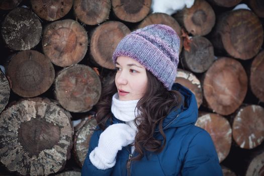 the beautiful young girl in a warm cap from wool of the alpaca in the winter forest. knitting
