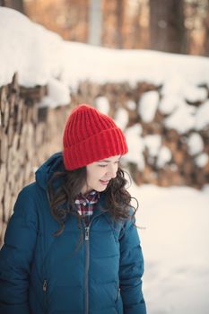 the beautiful young girl in a warm cap from wool of the alpaca in the winter forest. knitting