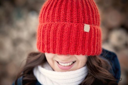 the beautiful young girl in a warm cap from wool of the alpaca in the winter forest. knitting
