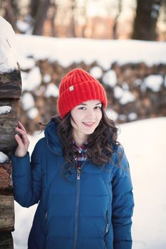 the beautiful young girl in a warm cap from wool of the alpaca in the winter forest. knitting