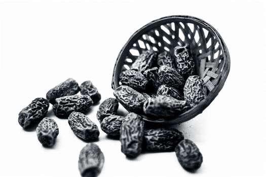 Close up shot of raw dried dates or kharek or sukhi khajoor or Phoenix dactylifera in a hamper isolated on white.