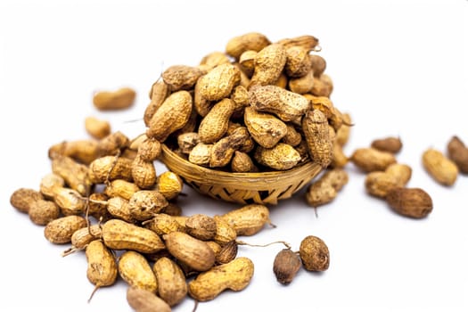 Close up of brown colored hamper having groundnuts or peanuts or moongaphalee or Arachis hypogaea or goober or monkey nut isolated on white.