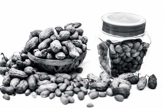 Close up of raw peanuts or groundnut isolated on white with some peeled in a separate bottle.