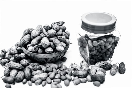 Close up of raw peanuts or groundnut isolated on white with some peeled in a separate bottle.