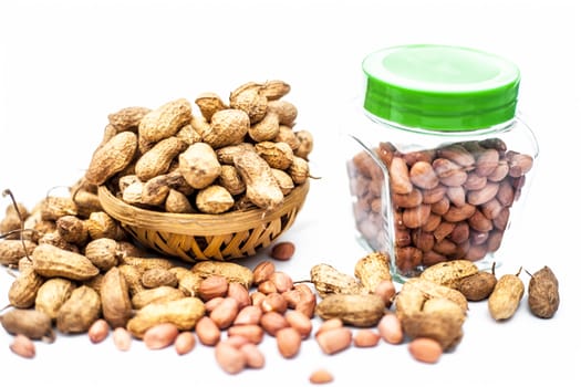 Close up of raw peanuts or groundnut isolated on white with some peeled in a separate bottle.