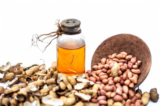 Close up of raw organic peanuts or ground nuts isolated on white along with its herbal organic extracted oil in a transparent bottle.