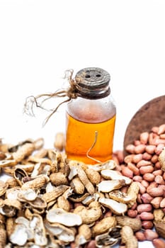 Close up of raw organic peanuts or ground nuts isolated on white along with its herbal organic extracted oil in a transparent bottle.