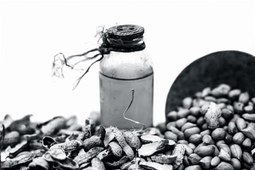 Close up of raw organic peanuts or ground nuts isolated on white along with its herbal organic extracted oil in a transparent bottle.