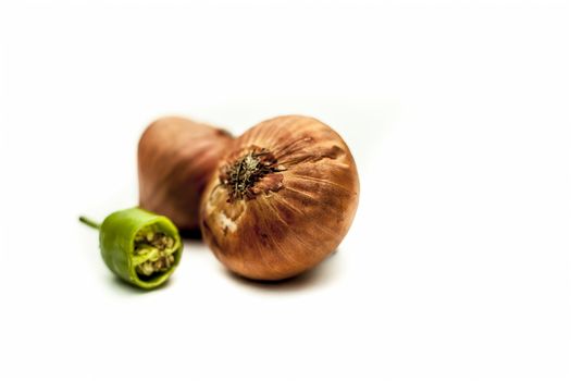 Raw organic two vegetables isolated on white which are onion or pyaaj or pyaaz along with cut chili or hari mirchi or lili mirchi.