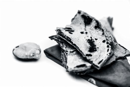 Close up of common or main ingredients of Malida isolated on white which are rot or bajri ki roti with jaggery in a small glass plate.