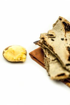 Close up of common or main ingredients of Malida isolated on white which are rot or bajri ki roti with jaggery in a small glass plate.