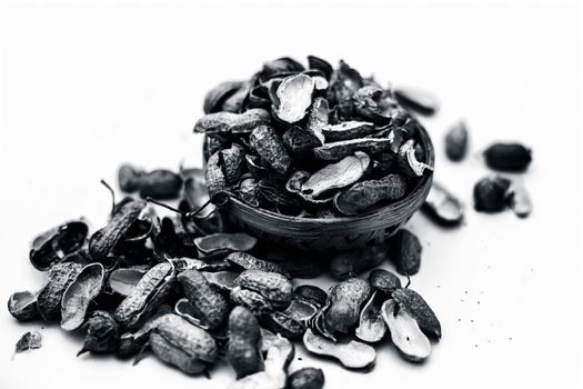 Close up of brown colored hamper having groundnuts or peanuts or moongaphalee or Arachis hypogaea or goober or monkey nut some in shells and some opened isolated on white.