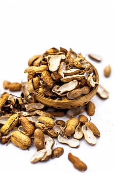 Close up of brown colored hamper having groundnuts or peanuts or moongaphalee or Arachis hypogaea or goober or monkey nut some in shells and some opened isolated on white.