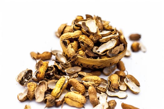 Close up of brown colored hamper having groundnuts or peanuts or moongaphalee or Arachis hypogaea or goober or monkey nut some in shells and some opened isolated on white.