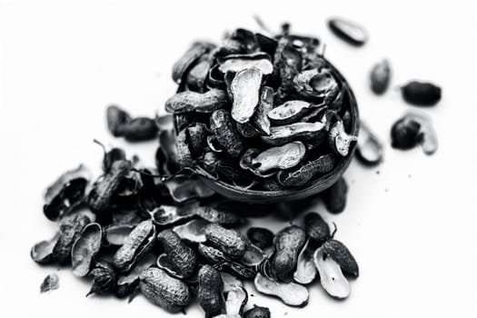 Close up of brown colored hamper having groundnuts or peanuts or moongaphalee or Arachis hypogaea or goober or monkey nut some in shells and some opened isolated on white.