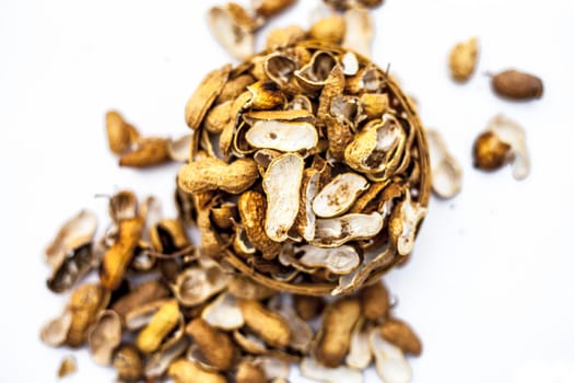 Close up of brown colored hamper having groundnuts or peanuts or moongaphalee or Arachis hypogaea or goober or monkey nut some in shells and some opened isolated on white.