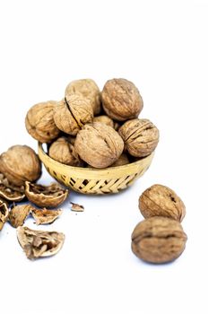 Close up of essential oil or essence of walnut or akhrot isolated on white in a small transparent glass bottle along with raw in shell walnuts or Juglans.