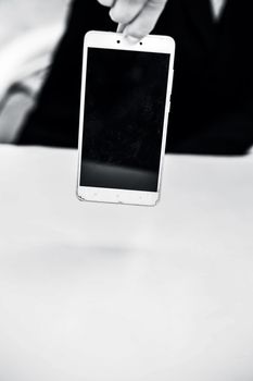 Close up of shot of hands of a business man wearing blue colored suit and holding a cell phone from the edge concept of loss in business isolated on white.