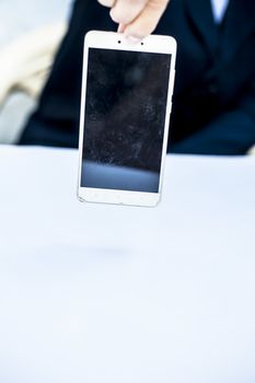 Close up of shot of hands of a business man wearing blue colored suit and holding a cell phone from the edge concept of loss in business isolated on white.