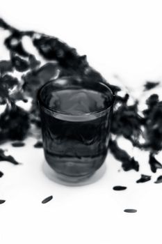 Close up shot of herbal organic fresh extract of peacock flowers in a transparent glass with flowers isolated on white.