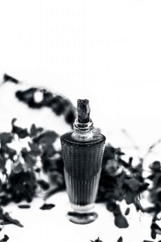 Close up shot of perfume or scent of peacock flower in a transparent bottle along with raw flowers isolated on white.