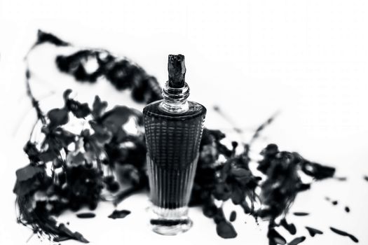 Close up shot of perfume or scent of peacock flower in a transparent bottle along with raw flowers isolated on white.