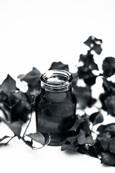 Close up shot of organic extracted oil of Bougainvillea isolated on white in a transparent glass bottle along with raw flowers.