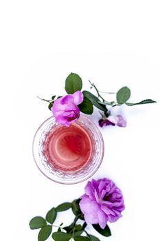 Close up view of organic fresh rose tea in a transparent glass cup isolated on white with raw roses.