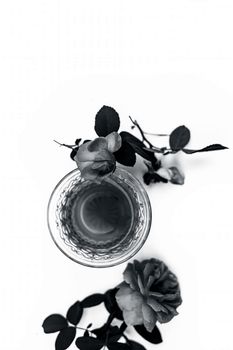 Close up view of organic fresh rose tea in a transparent glass cup isolated on white with raw roses.