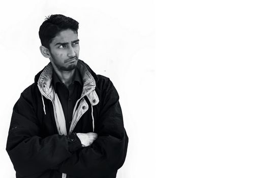 Portrait shot of a young beard man wearing brown colored shirt and a black colored jacket expressing curiousness by looking at the blank side.