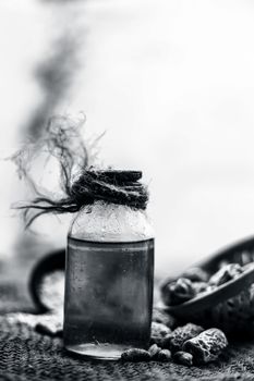 Close up of raw organic kharek or dried dates in a hamper or basket with its extracted herbal beneficial oil in a transparent bottle on gunny bag's surface.