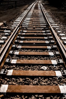 Close up of railway tracks passing or running straight through a forest type area with having surroundings dried out.