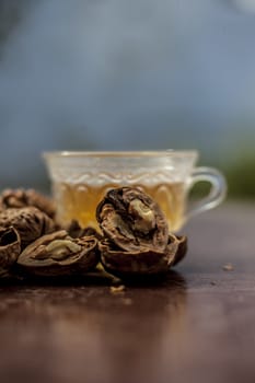 Close up of herbal organic tea of wall nut or walnut tea in a transparent glass cup with raw wall nut in shell and broken also.