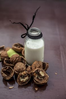 Close up of walnut or akhrot on wooden surface in a clay bowl with a small transparent bottle used to make dry fruit milkshake.