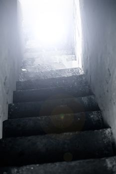 Vertical shot of stairs going downwards without end or ending with some brightness.;