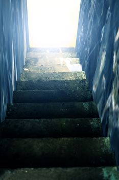 Vertical shot of stairs going downwards without end or ending with some brightness.;
