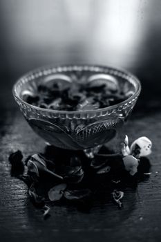 Close up of rose water in a transparent glass bowl on wooden surface in black white colors.