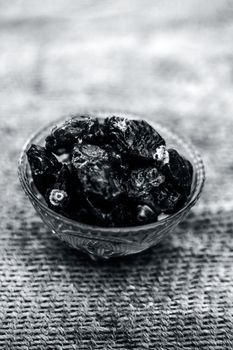 Close up of shot of raw organic dates or khajoor or Phoenix dactylifera in a glass bowl on a gunny bag background.