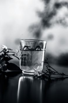 Close up of extract of Indian jasmine flower or juhi or Jasminum Auriculatum on wooden surface in a transparent glass with raw flowers.