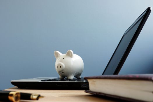 Piggy bank on a laptop. Online savings or banking concept.