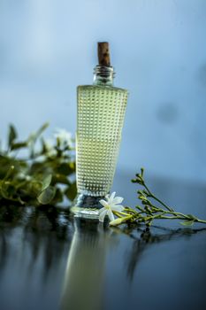 Close up of spray or perfume of Indian jasmine flower or juhi or Jasminum Auriculatum on wooden surface in a small bottle with raw flowers.