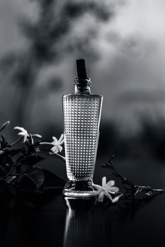 Close up of spray or perfume of Indian jasmine flower or juhi or Jasminum Auriculatum on wooden surface in a small bottle with raw flowers.