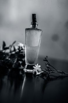 Close up of spray or perfume of Indian jasmine flower or juhi or Jasminum Auriculatum on wooden surface in a small bottle with raw flowers.
