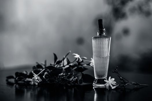 Close up of spray or perfume of Indian jasmine flower or juhi or Jasminum Auriculatum on wooden surface in a small bottle with raw flowers.