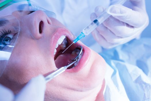 Dentist about to give injection to terrified patient at the dental clinic