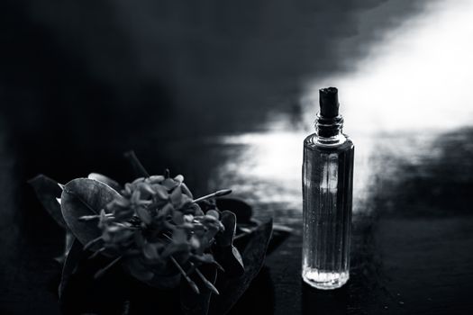 Close up of red colored pentas flower or Egyptian Star Flower or jasmine on wooden surface with its extracted spray or perfume in a transparent glass bottle.